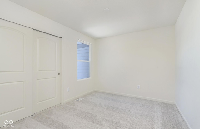 unfurnished bedroom featuring light carpet, multiple windows, and a closet