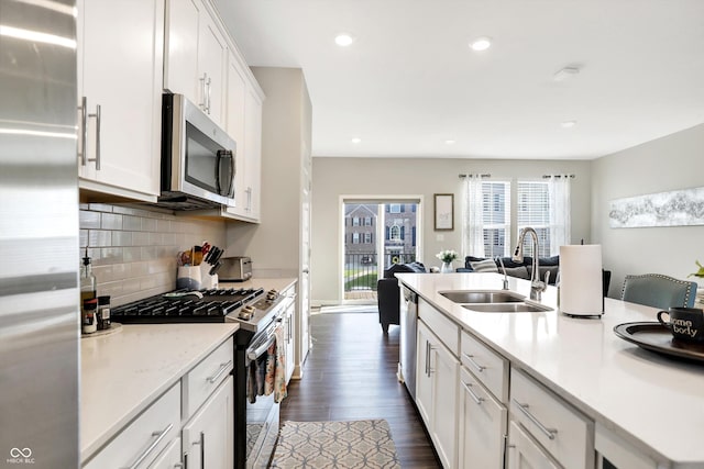 kitchen with sink, white cabinetry, appliances with stainless steel finishes, dark hardwood / wood-style flooring, and decorative backsplash