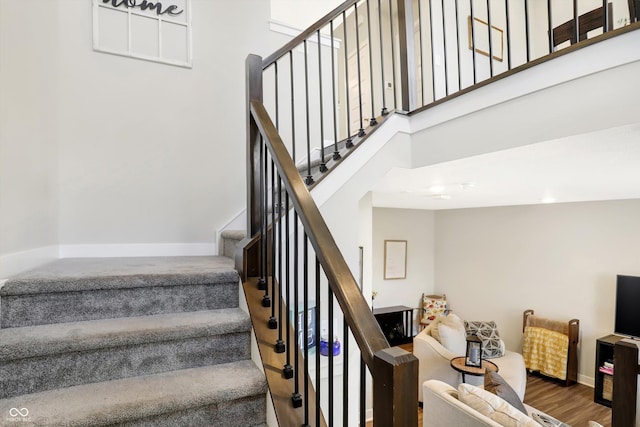 stairs with hardwood / wood-style floors and a high ceiling