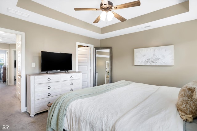 carpeted bedroom featuring ceiling fan and a tray ceiling