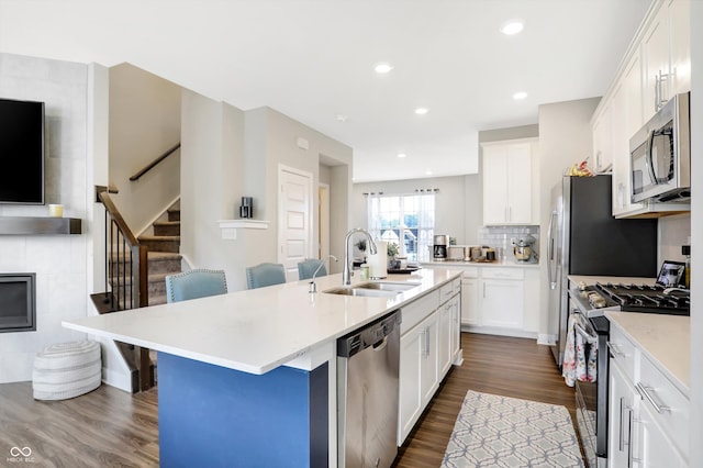 kitchen with sink, a breakfast bar area, appliances with stainless steel finishes, a kitchen island with sink, and white cabinets