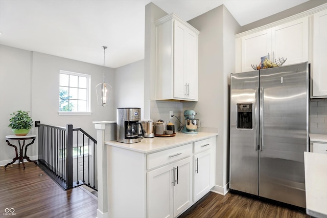 kitchen featuring dark wood-type flooring, white cabinetry, stainless steel fridge, pendant lighting, and decorative backsplash