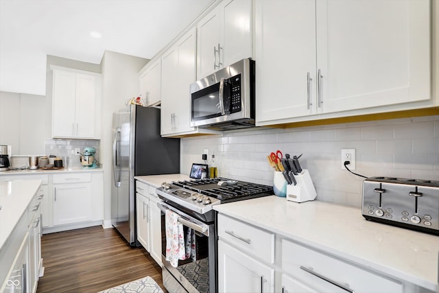 kitchen with tasteful backsplash, dark hardwood / wood-style flooring, stainless steel appliances, and white cabinets