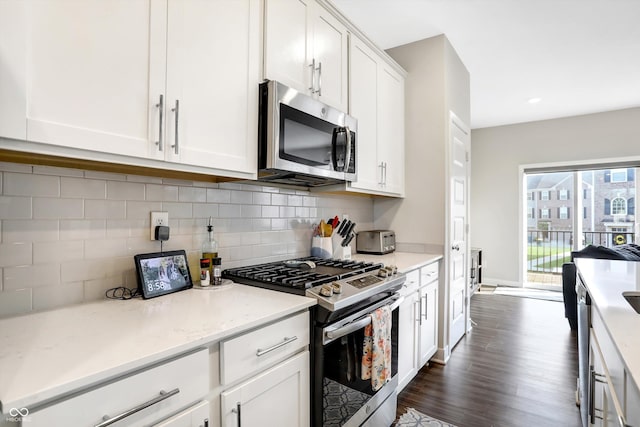 kitchen with dark hardwood / wood-style floors, tasteful backsplash, white cabinets, light stone counters, and stainless steel appliances