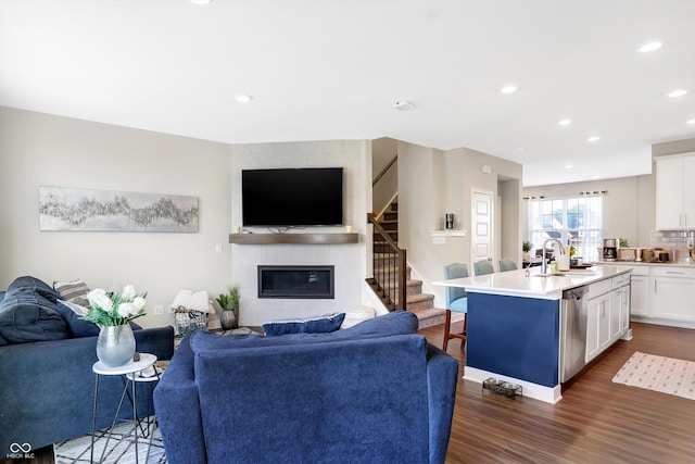 living room with sink, dark wood-type flooring, and a large fireplace