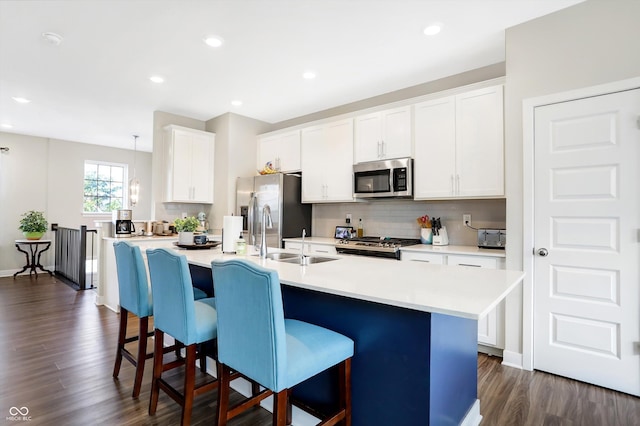 kitchen with sink, a breakfast bar area, an island with sink, and appliances with stainless steel finishes