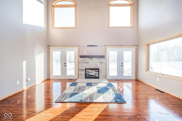 unfurnished living room featuring french doors, wood-type flooring, and a high ceiling