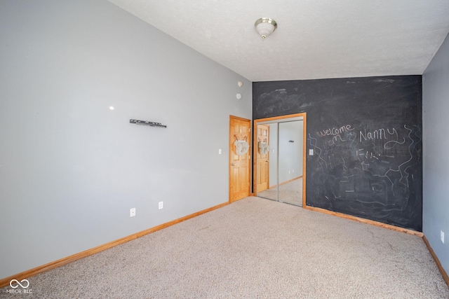 spare room with lofted ceiling, carpet floors, and a textured ceiling