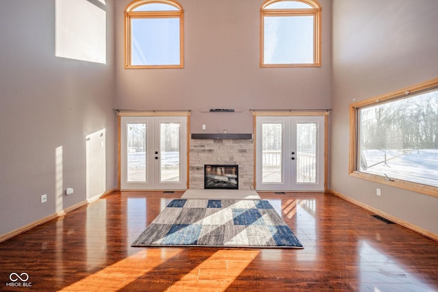 unfurnished living room featuring a towering ceiling, a fireplace, and french doors