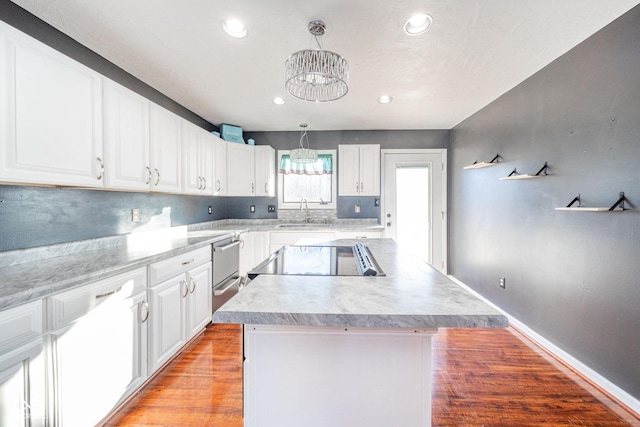 kitchen with range, light hardwood / wood-style floors, white cabinets, a kitchen island, and decorative light fixtures