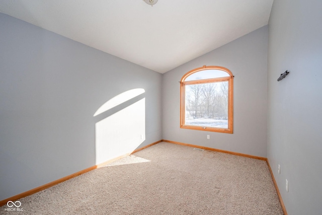 spare room featuring vaulted ceiling and light colored carpet