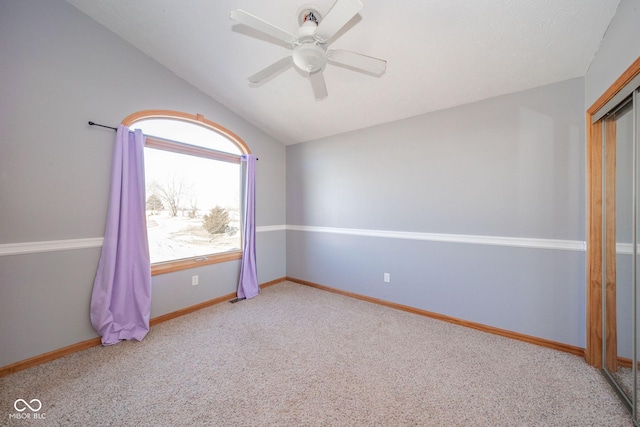 spare room featuring lofted ceiling, light colored carpet, and ceiling fan