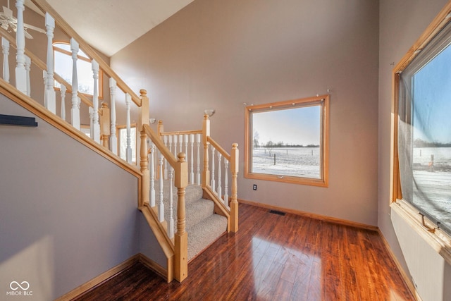 stairs featuring lofted ceiling, radiator, and hardwood / wood-style flooring