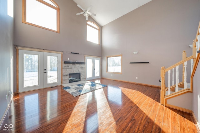 living room with french doors, ceiling fan, a fireplace, hardwood / wood-style floors, and a high ceiling