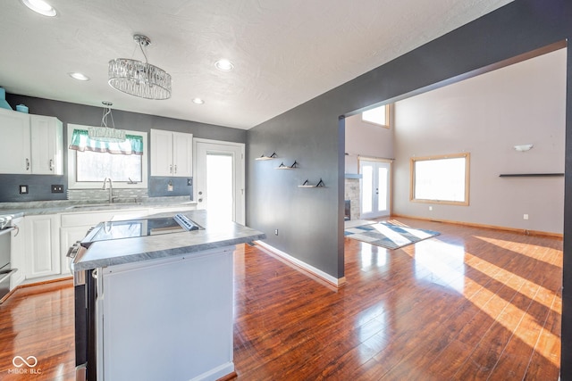 kitchen featuring sink, hanging light fixtures, white cabinets, and a center island