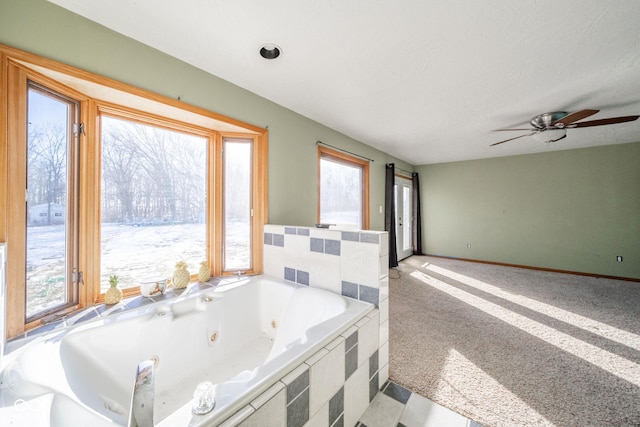 bathroom featuring a relaxing tiled tub and a healthy amount of sunlight