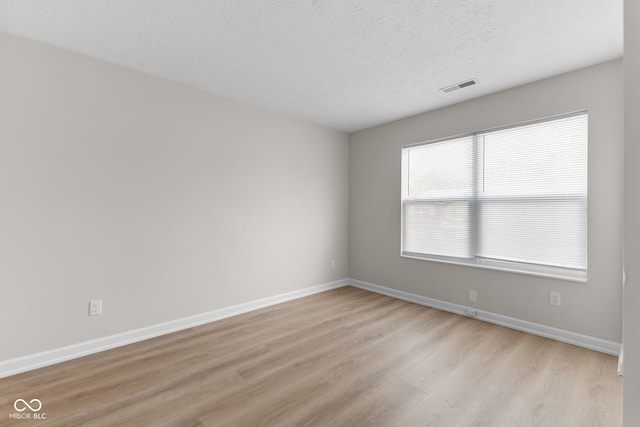 unfurnished room featuring light hardwood / wood-style flooring and a textured ceiling