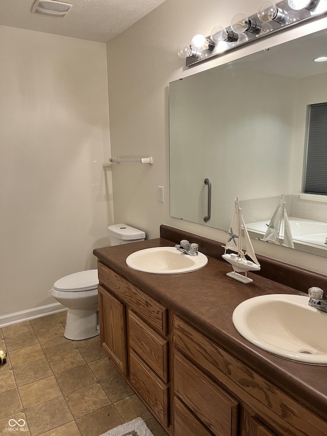 bathroom with vanity, toilet, a bath, and a textured ceiling