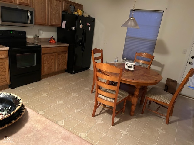 kitchen featuring light tile patterned floors, decorative light fixtures, and black appliances