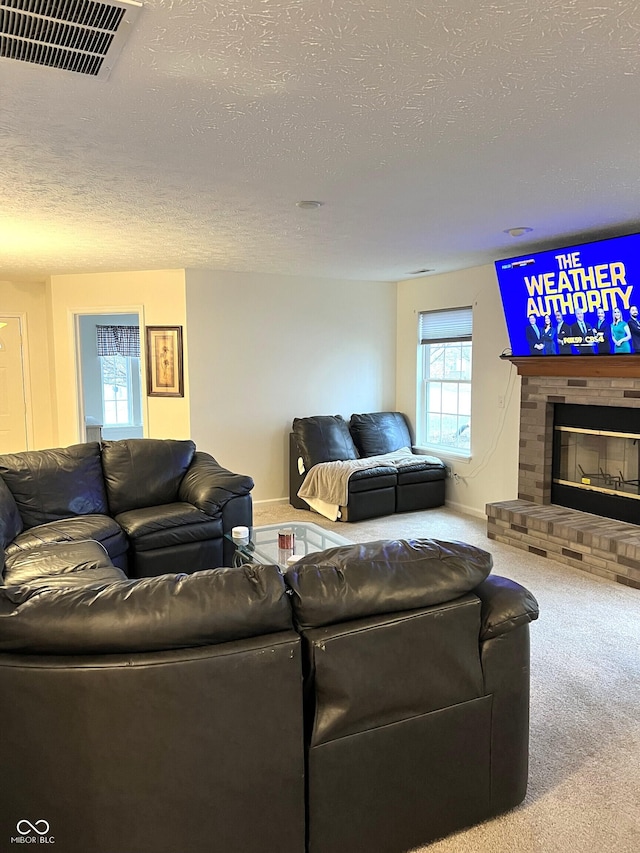 carpeted living room featuring a brick fireplace and a textured ceiling