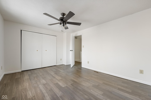 unfurnished bedroom with hardwood / wood-style floors, ceiling fan, and a closet