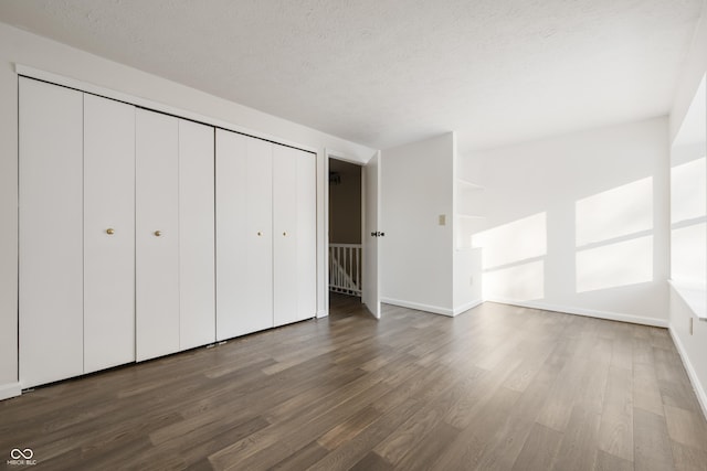 unfurnished bedroom with a closet, dark hardwood / wood-style floors, and a textured ceiling