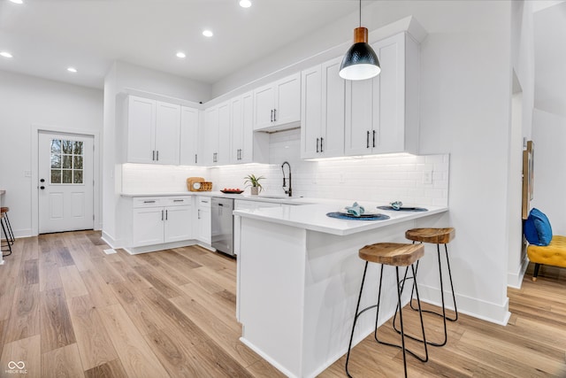 kitchen with pendant lighting, stainless steel dishwasher, kitchen peninsula, and white cabinets