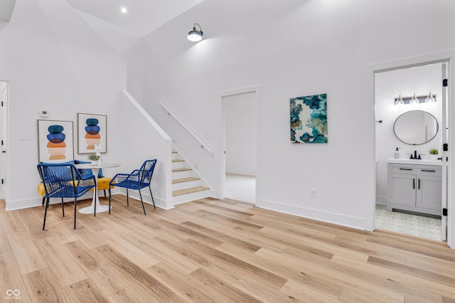 living area with high vaulted ceiling, light hardwood / wood-style floors, and sink