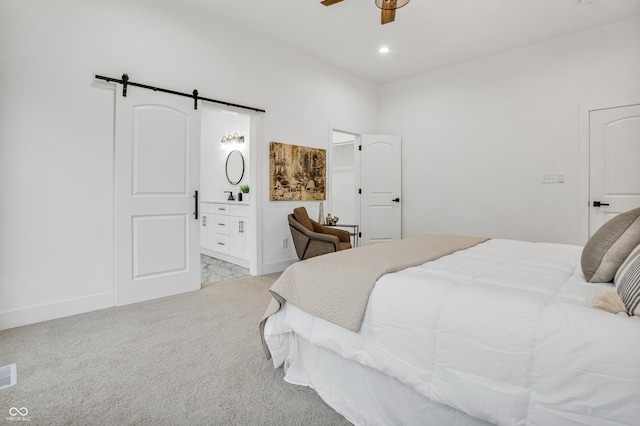 carpeted bedroom with connected bathroom, a barn door, and ceiling fan