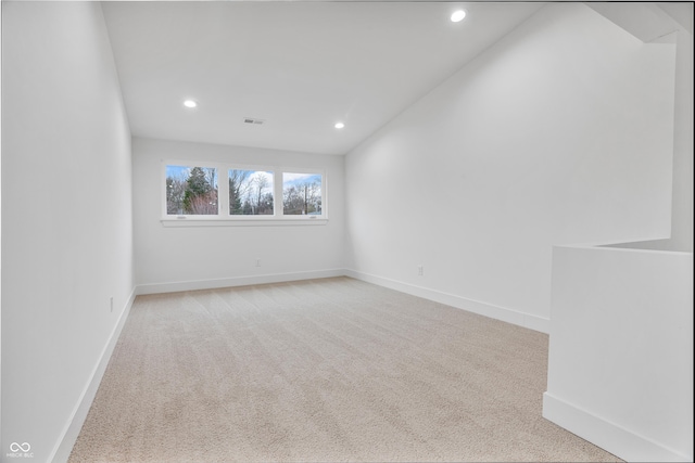 carpeted empty room featuring lofted ceiling