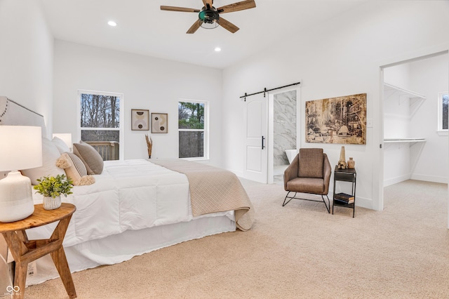 carpeted bedroom with a barn door and ceiling fan