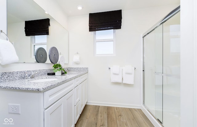 bathroom with wood-type flooring, an enclosed shower, and vanity