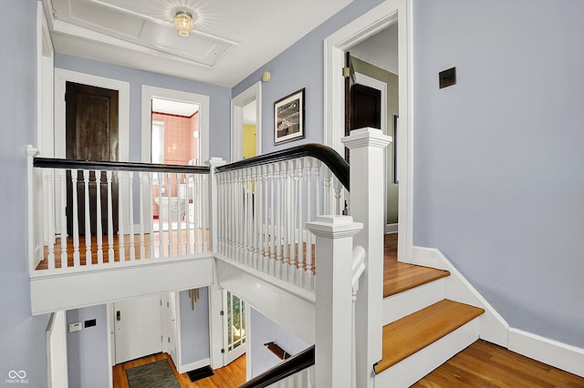 stairs featuring a high ceiling, baseboards, and wood finished floors