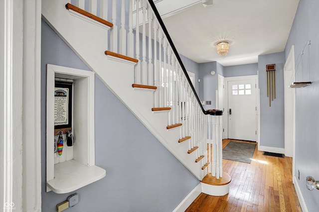 entrance foyer with visible vents, stairway, baseboards, and hardwood / wood-style flooring