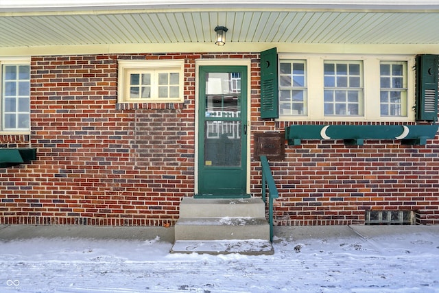 snow covered property entrance with brick siding