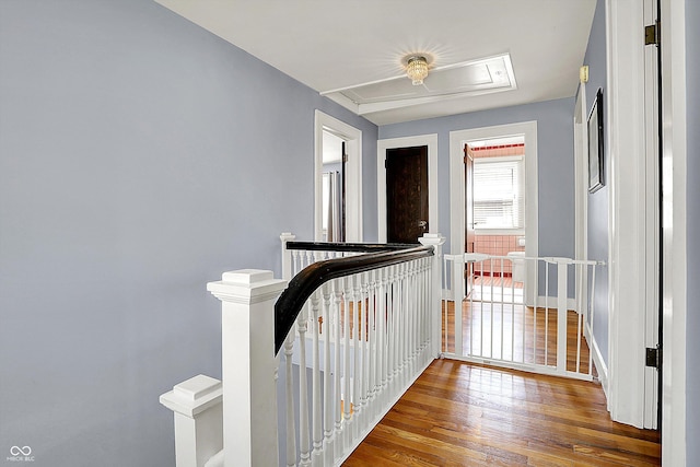 hall featuring hardwood / wood-style flooring, an upstairs landing, and baseboards