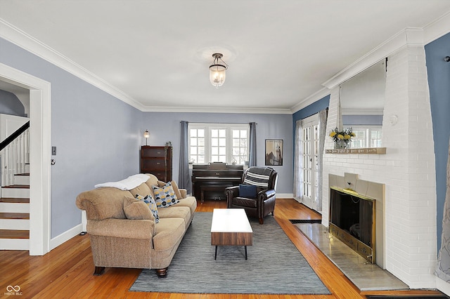 living area with crown molding, a fireplace, and wood finished floors