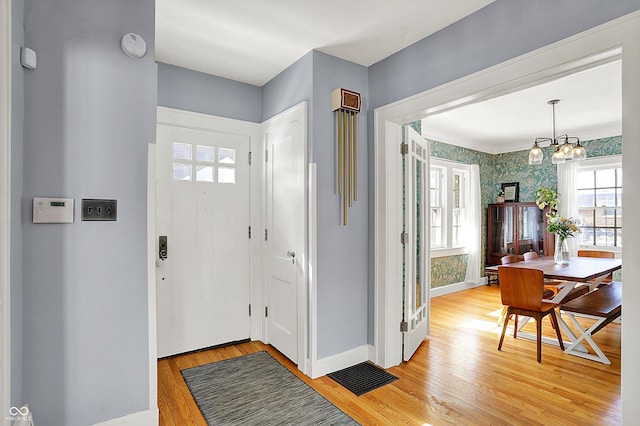 foyer featuring visible vents, light wood-style flooring, an inviting chandelier, baseboards, and wallpapered walls