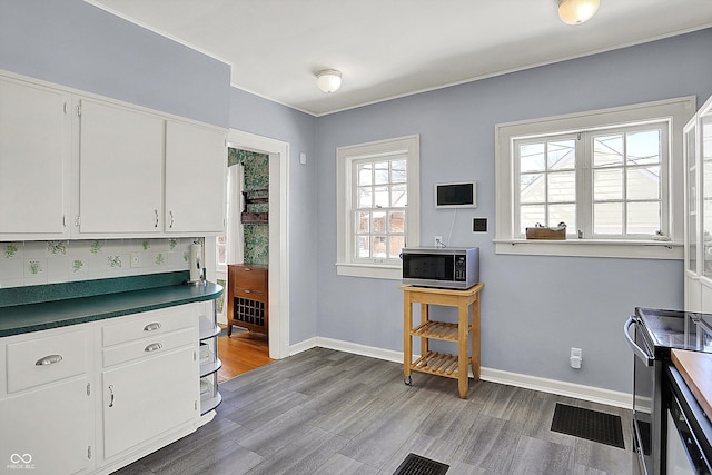 kitchen featuring stainless steel appliances, wood finished floors, white cabinetry, visible vents, and baseboards