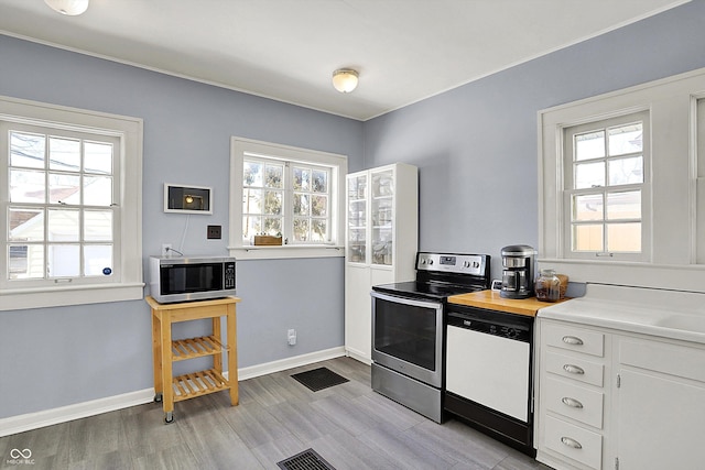 kitchen featuring baseboards, white cabinets, visible vents, appliances with stainless steel finishes, and light countertops