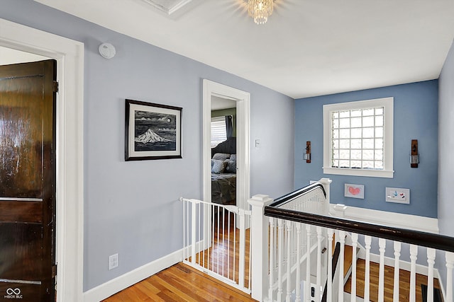 hall featuring baseboards, an upstairs landing, and wood finished floors