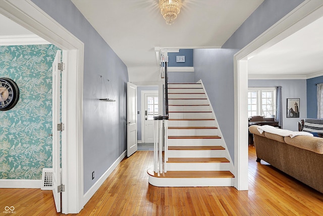 foyer featuring visible vents, wallpapered walls, hardwood / wood-style floors, baseboards, and stairs