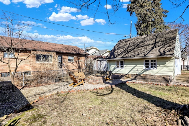 back of house featuring an outdoor fire pit, a lawn, a patio, roof with shingles, and fence