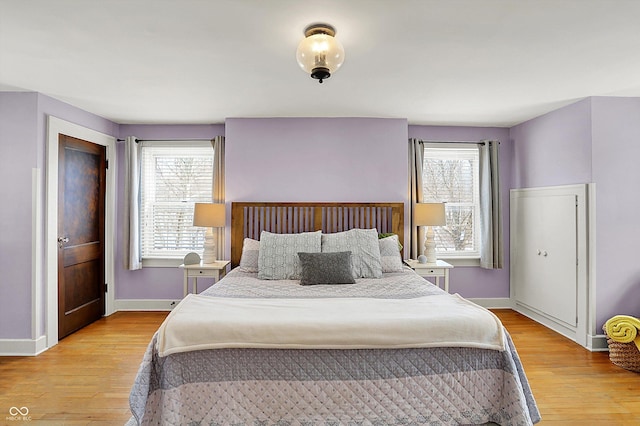 bedroom with baseboards, multiple windows, and light wood-style floors