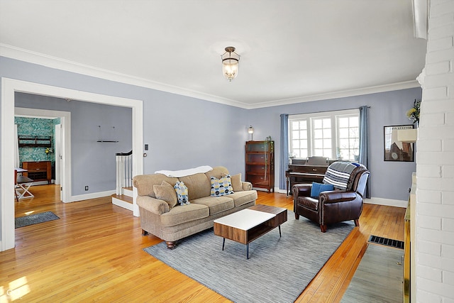 living area with baseboards, stairway, light wood-style flooring, and crown molding