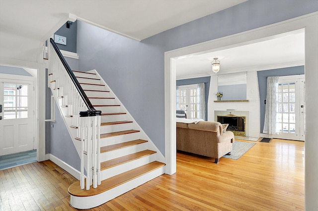 stairway featuring a brick fireplace, baseboards, and hardwood / wood-style floors