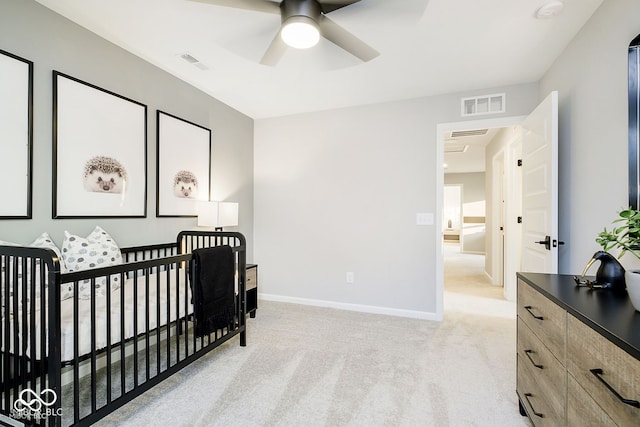 bedroom featuring a nursery area, baseboards, visible vents, and light carpet