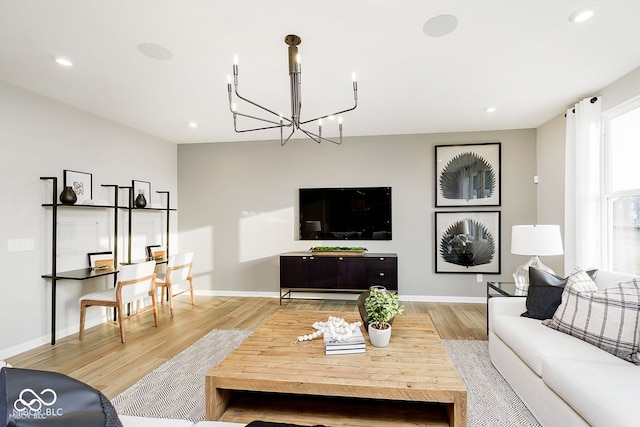 living room featuring an inviting chandelier, light wood-style flooring, and baseboards