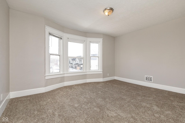 carpeted empty room featuring a textured ceiling