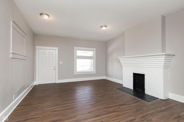 unfurnished living room with a brick fireplace and dark hardwood / wood-style floors